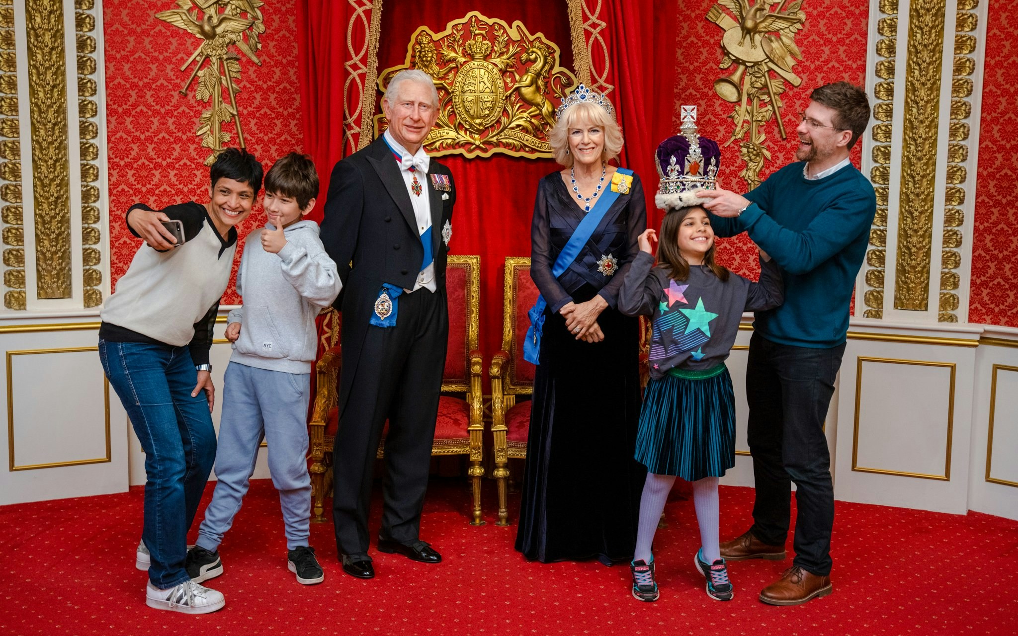 Visitors posing with King Charles III wax figure at Madame Tussauds London.