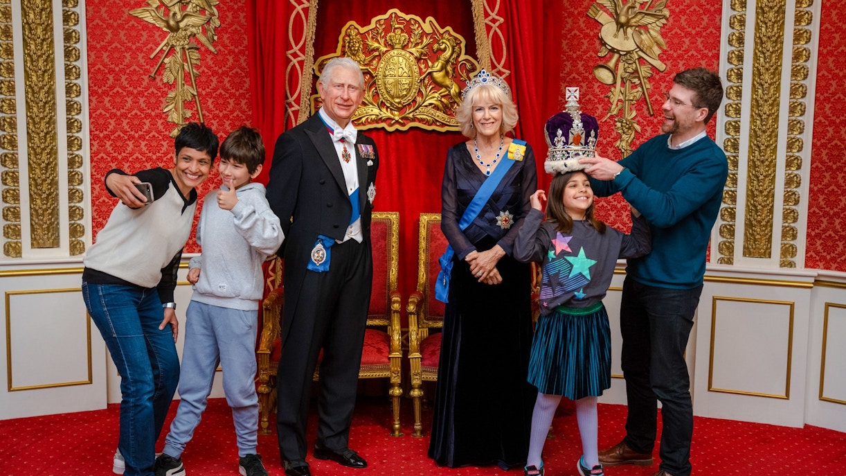 Visitors posing with King Charles III wax figure at Madame Tussauds London.