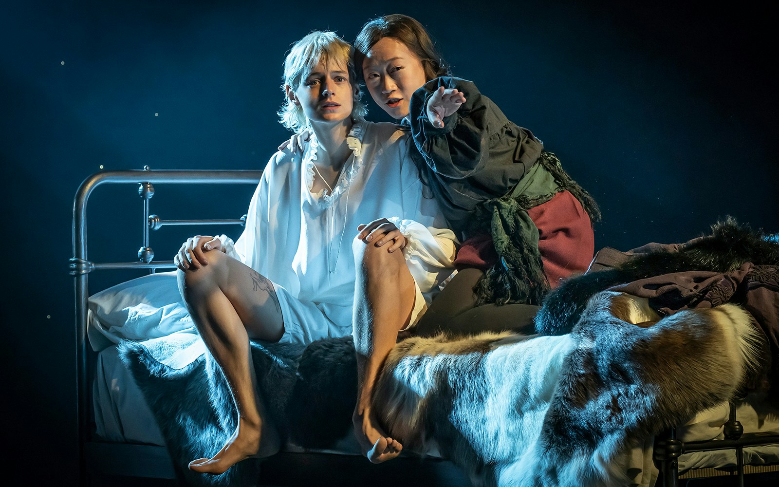 Two actors in period costumes on a bed during a theatrical performance in Orlando.