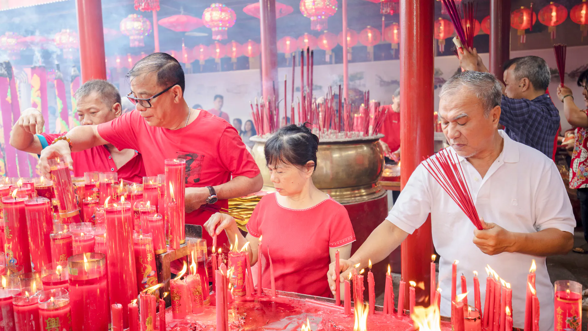 People lighting incense and candles at a temple in Jakarta during a cultural ceremony.
