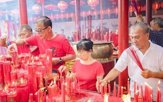 People lighting incense and candles at a temple in Jakarta during a cultural ceremony.