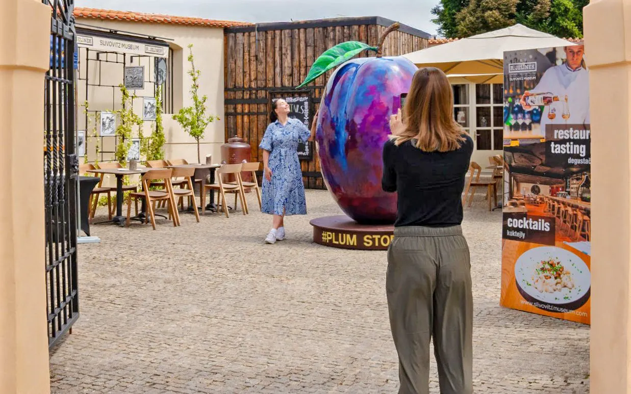 Visitors at Slivovitz Museum, Prague, near a large plum sculpture.
