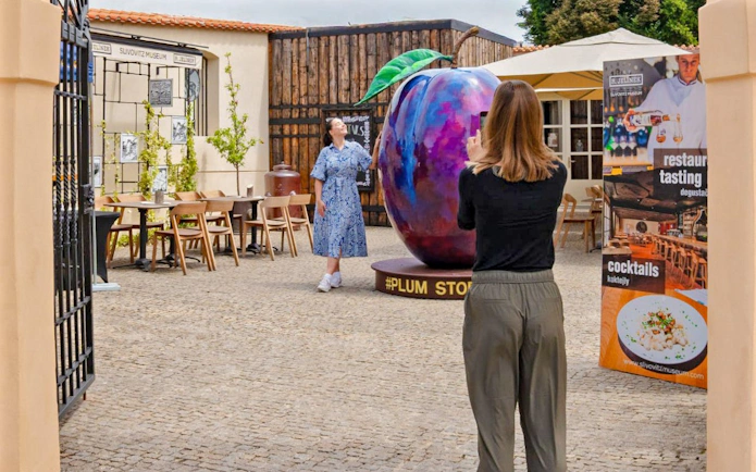 Visitors at Slivovitz Museum, Prague, near a large plum sculpture.