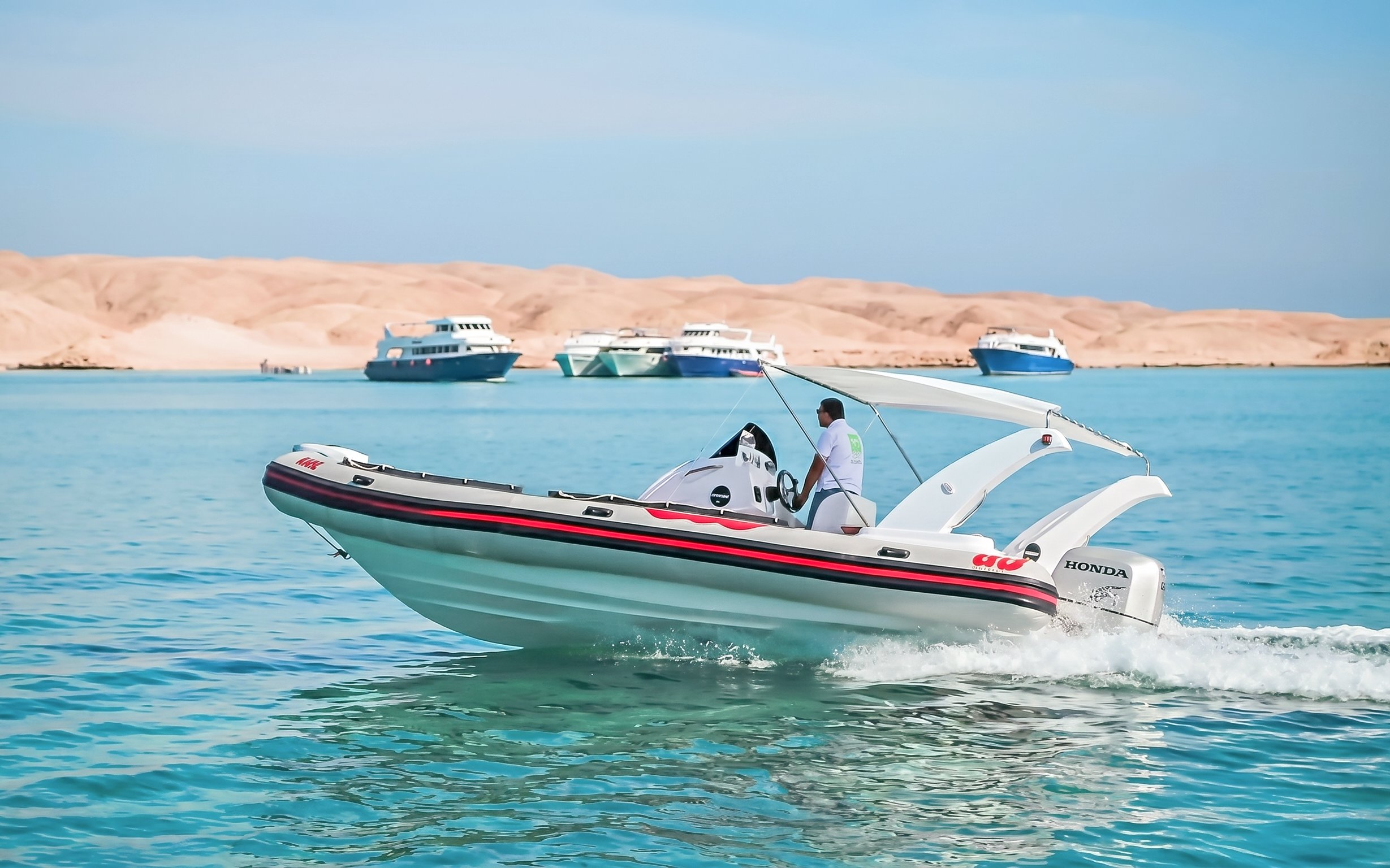 Private speedboat cruising near Orange Bay, Giftun Island, with distant yachts, Hurghada.