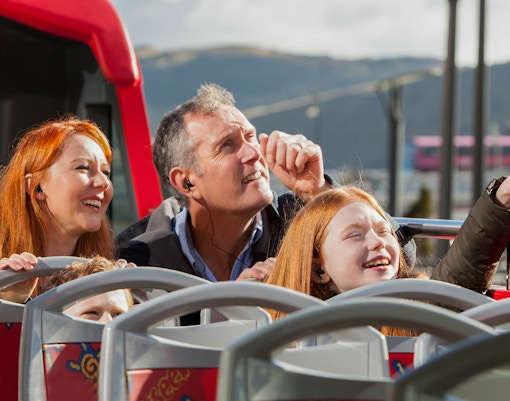 Family enjoying Edinburgh sights on a hop-on hop-off bus tour.