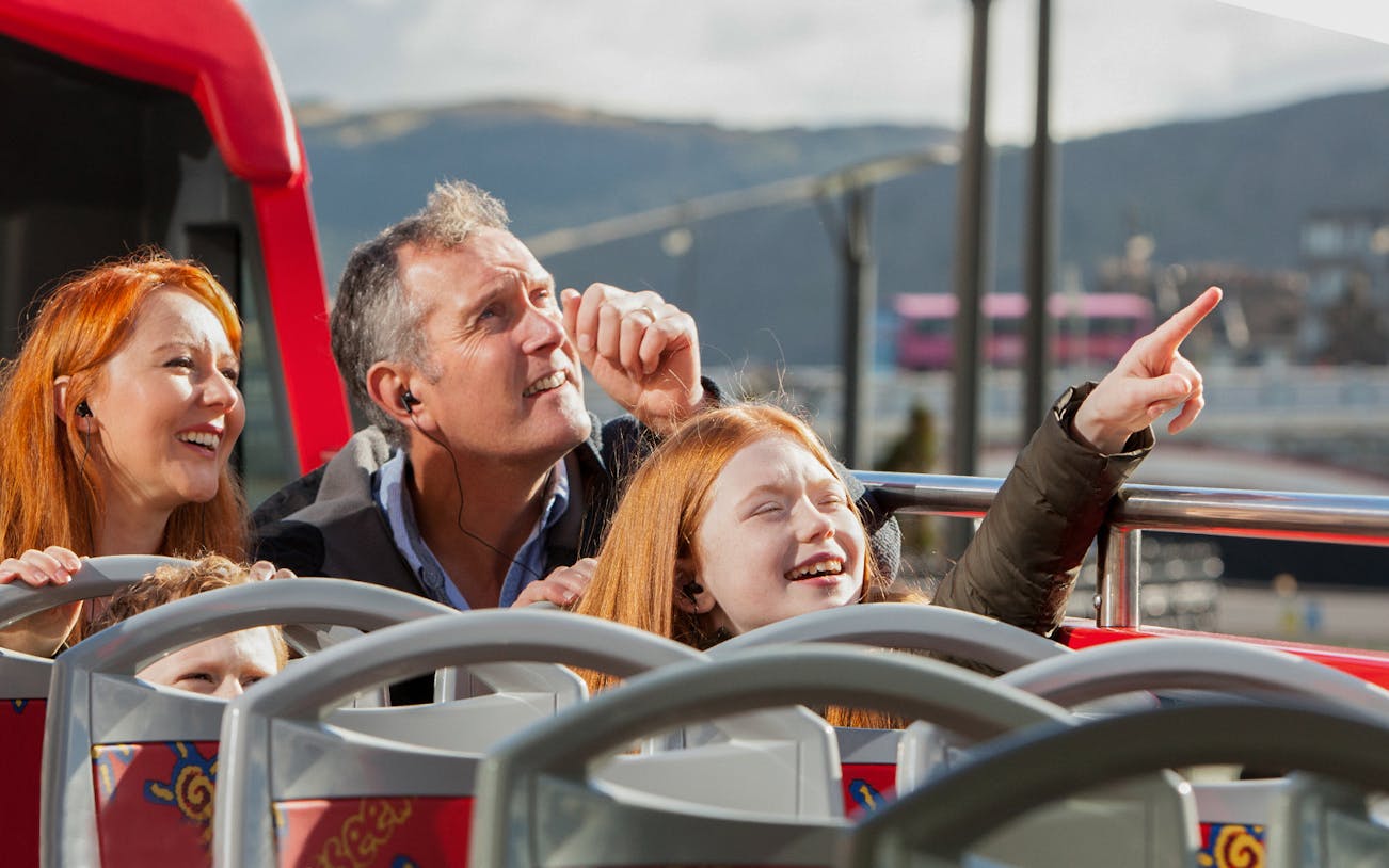 Family enjoying Edinburgh sights on a hop-on hop-off bus tour.