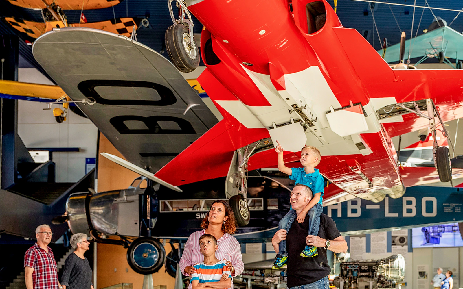 Family observing vintage aircraft at Swiss Museum of Transport, Lucerne.