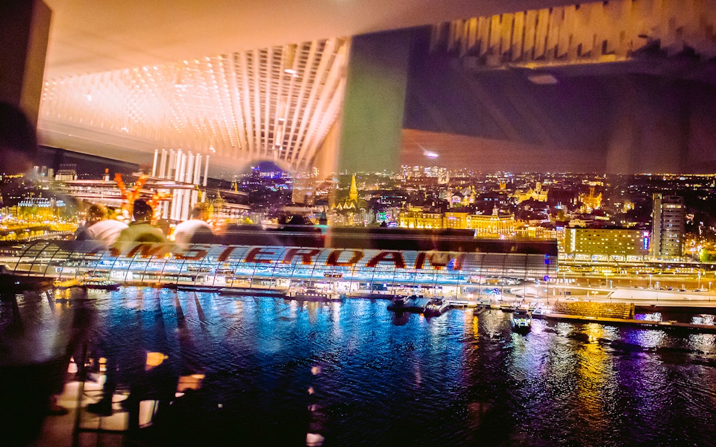 View of Amsterdam cityscape at night from A'DAM Lookout with reflections on the water.