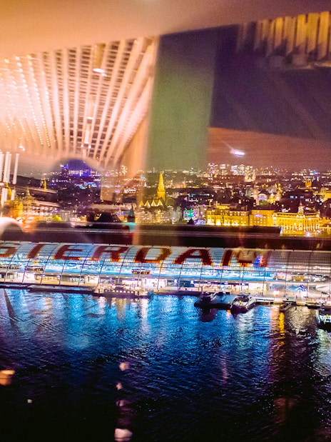 View of Amsterdam cityscape at night from A'DAM Lookout with reflections on the water.