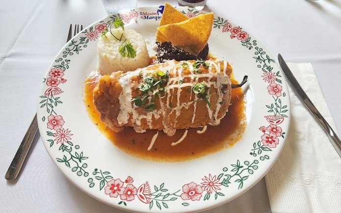 Chiles en nogada dish served with rice and tortilla chips on a decorative plate.