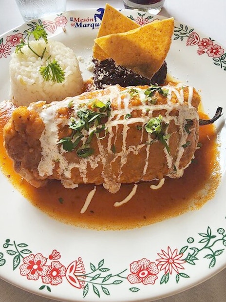 Chiles en nogada dish served with rice and tortilla chips on a decorative plate.