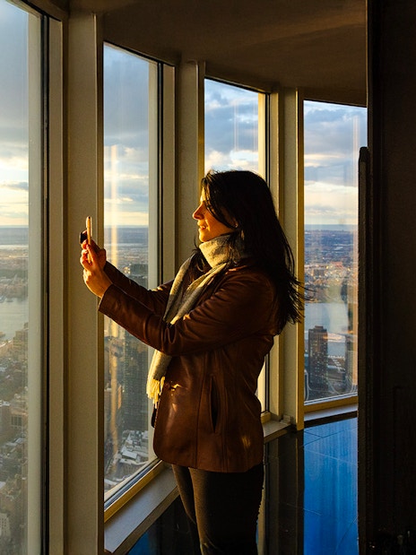 Guest taking photo at Empire State Building observatory with city view.
