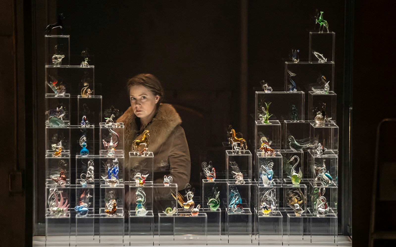 Glass figurines display with a person observing, related to "The Glass Menagerie.