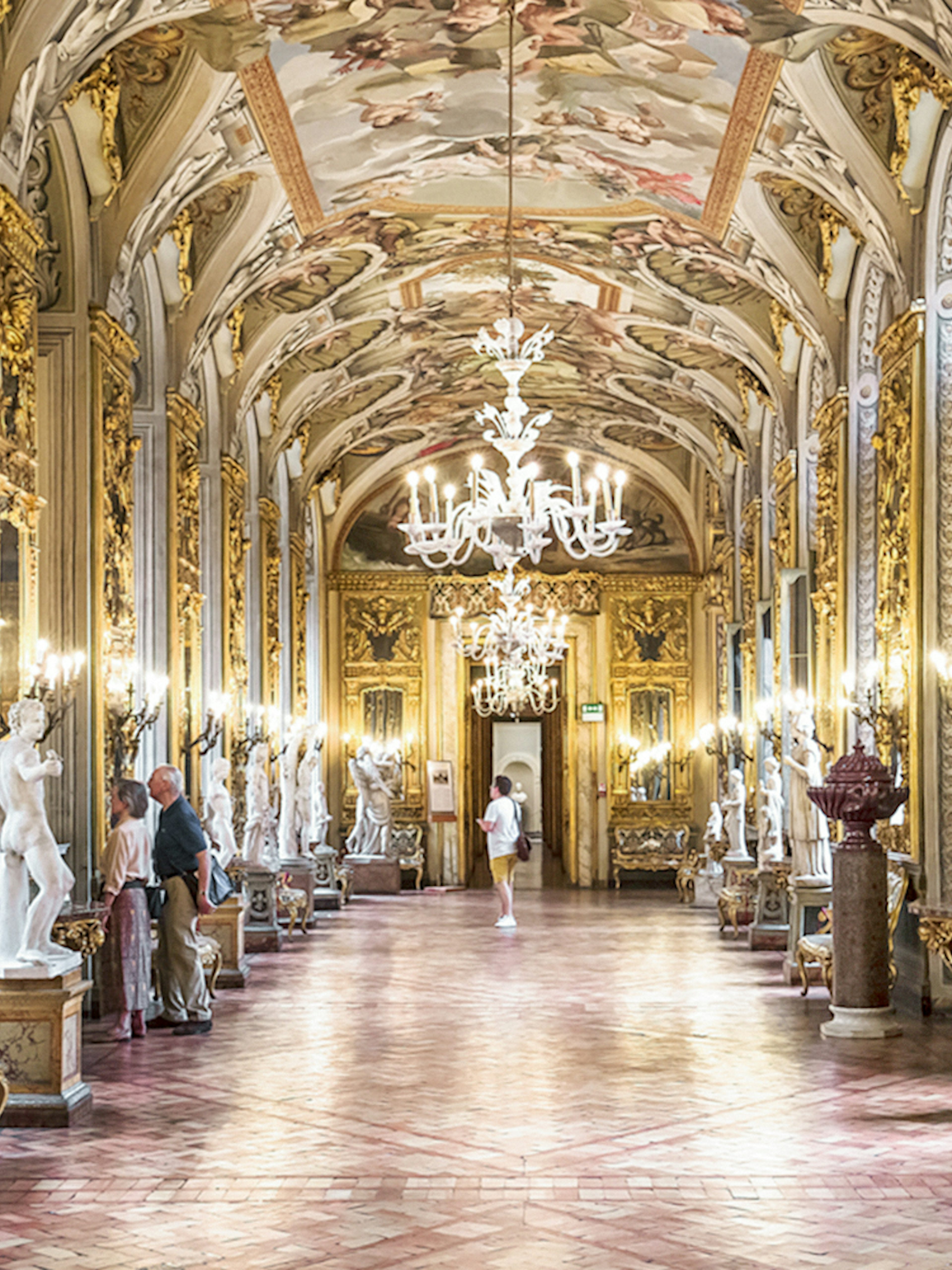 Doria Pamphilj Gallery hall with ornate ceiling, chandeliers, and classical statues in Rome.