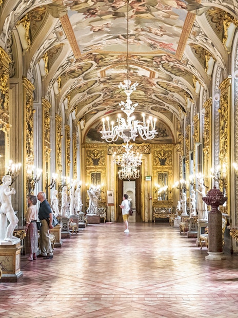Doria Pamphilj Gallery hall with ornate ceiling, chandeliers, and classical statues in Rome.