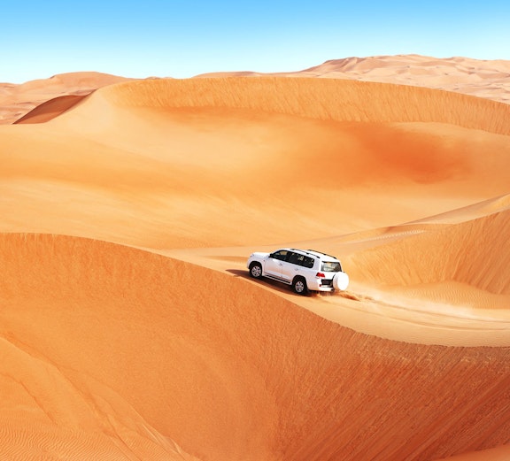 Car driving on sand dunes during a Dubai desert safari.