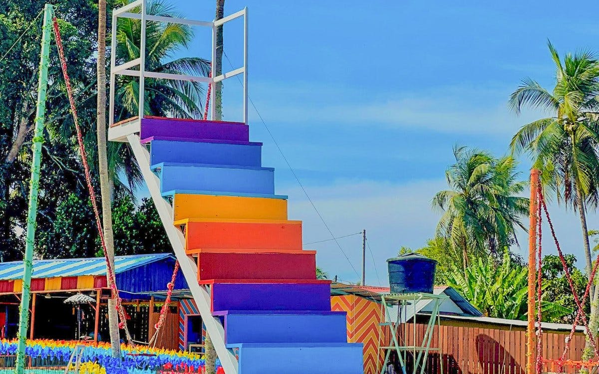 Colorful staircase at De Windmill Selfie Park with palm trees in the background.