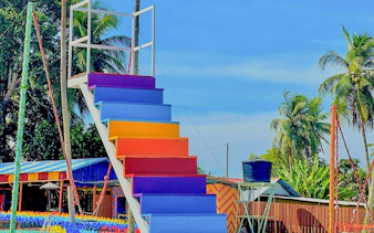 Colorful staircase at De Windmill Selfie Park with palm trees in the background.