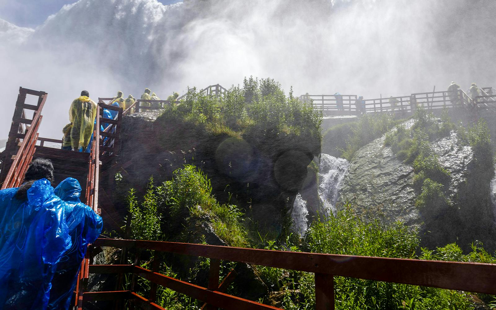 Visitors in raincoats on wooden walkways near Niagara Falls USA.