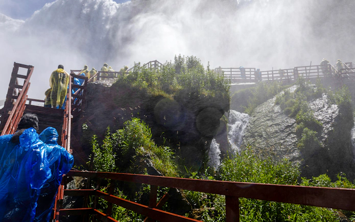 Visitors in raincoats on wooden walkways near Niagara Falls USA.