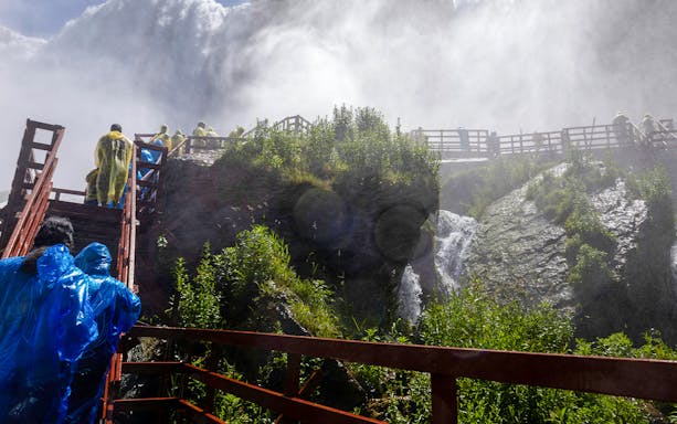 Visitors in raincoats on wooden walkways near Niagara Falls USA.