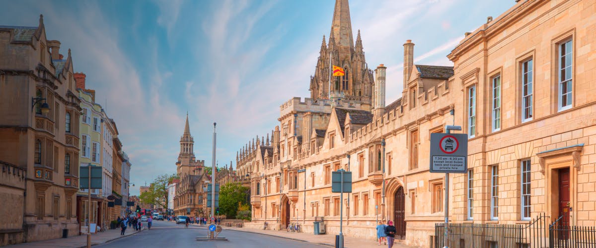 Street view of Oxford, UK, featuring historic university buildings and a church spire.