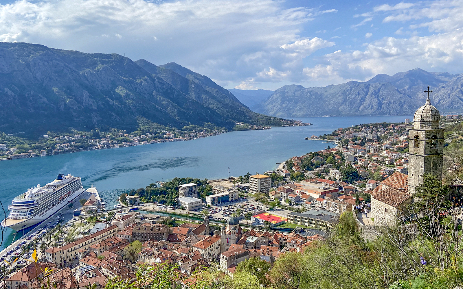 Kotor Bay view with cruise ship, mountains, and historic buildings in Montenegro.