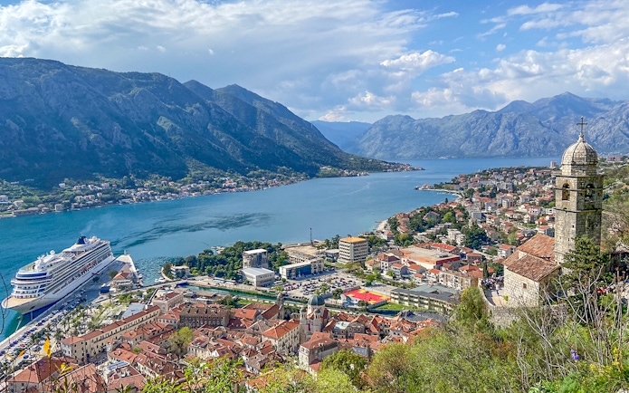 Kotor Bay view with cruise ship, mountains, and historic buildings in Montenegro.