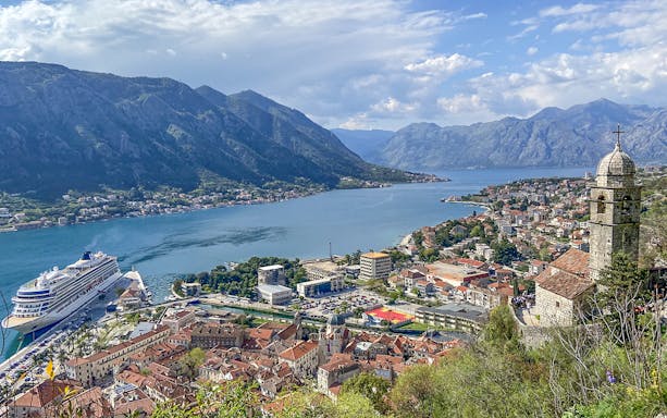 Kotor Bay view with cruise ship, mountains, and historic buildings in Montenegro.