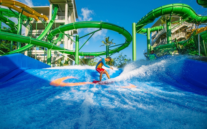 Boy surfing on Flow Rider at Waterbom Bali water park, Indonesia.