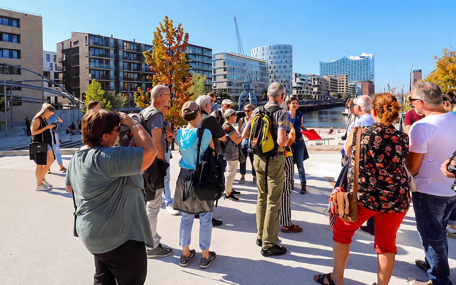 Tour group exploring HafenCity with Elbphilharmonie in the background, Hamburg.