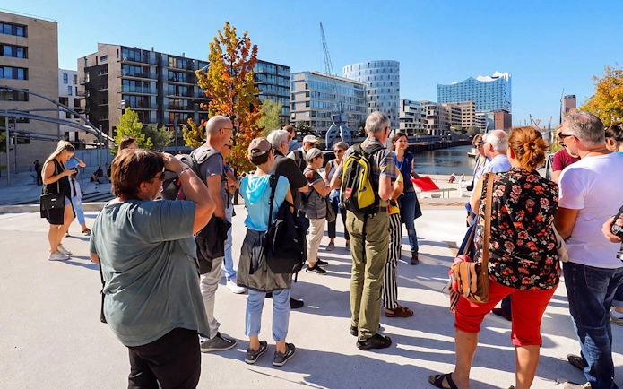 Tour group exploring HafenCity with Elbphilharmonie in the background, Hamburg.