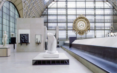 Interior of Musée d'Orsay, Paris, featuring sculptures and a large ornate clock.