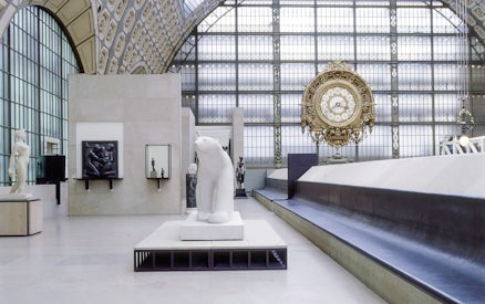 Interior of Musée d'Orsay, Paris, featuring sculptures and a large ornate clock.
