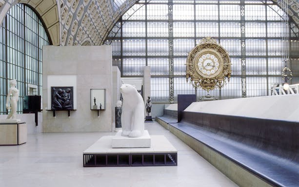 Interior of Musée d'Orsay, Paris, featuring sculptures and a large ornate clock.