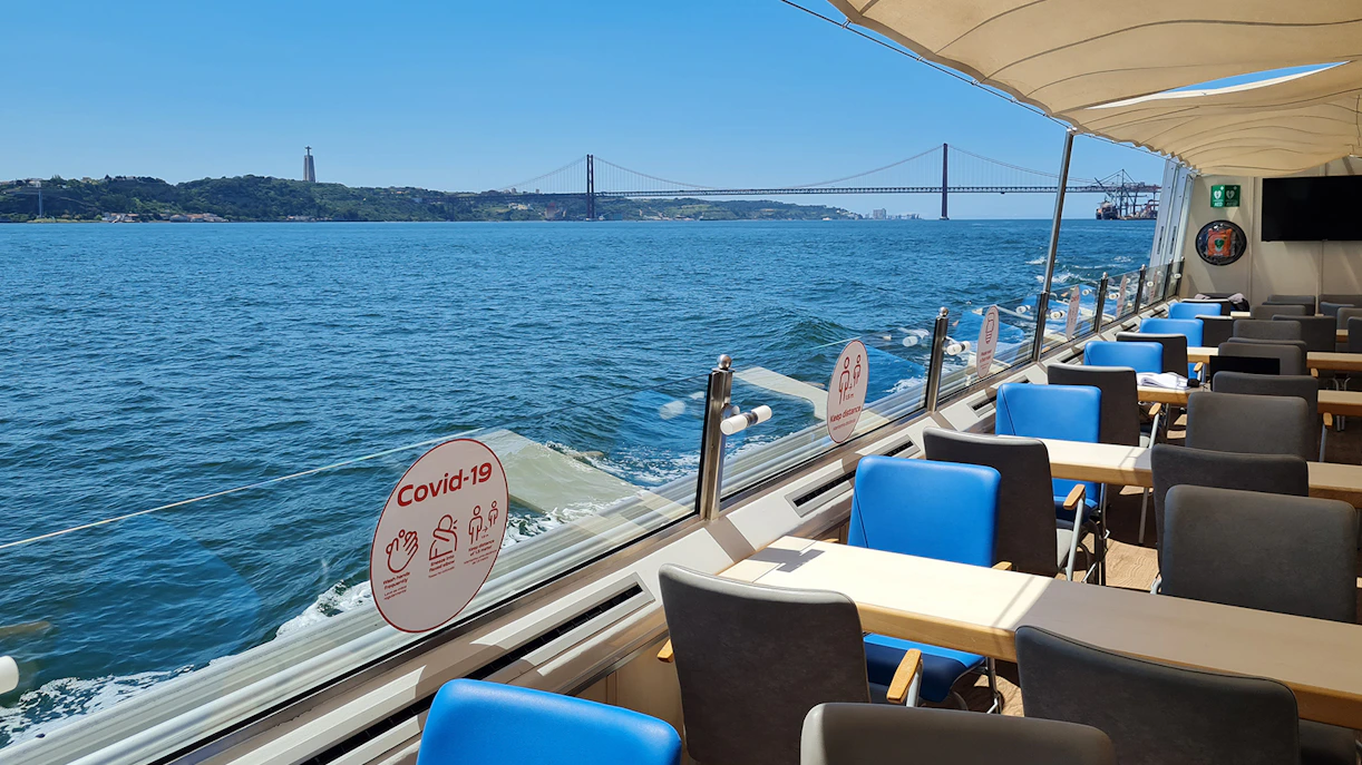 Interior of a boat on the Tagus River with views of the 25 de Abril Bridge in Lisbon.