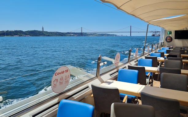 Interior of a boat on the Tagus River with views of the 25 de Abril Bridge in Lisbon.