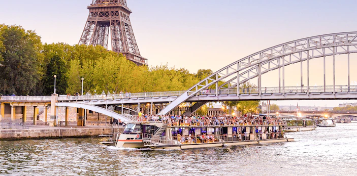 Seine River cruise boat near Eiffel Tower and bridge in Paris.