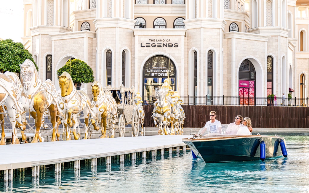 Couple enjoying a boat ride at The Land of Legends theme park with golden horse statues.