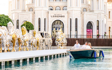 Couple enjoying a boat ride at The Land of Legends theme park with golden horse statues.