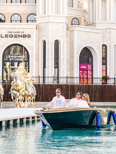 Couple enjoying a boat ride at The Land of Legends theme park with golden horse statues.