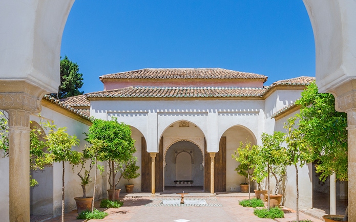 Roman Theater and Alcazaba Castle courtyard with arches and potted trees in Málaga.