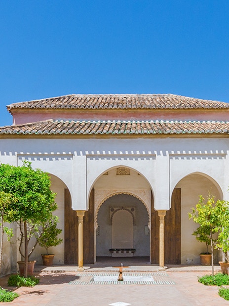 Roman Theater and Alcazaba Castle courtyard with arches and potted trees in Málaga.