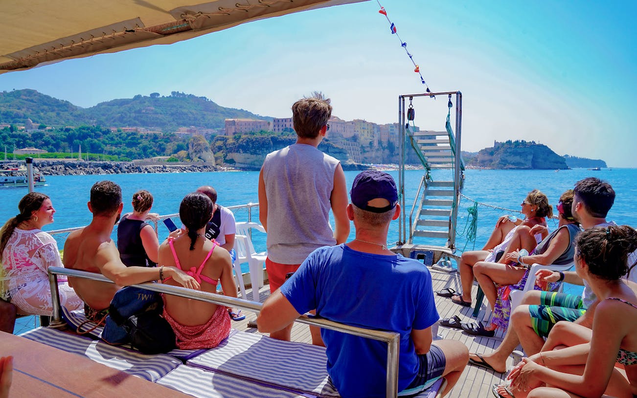 Tourists enjoying a boat trip near Tropea with views of Capo Vaticano coastline.