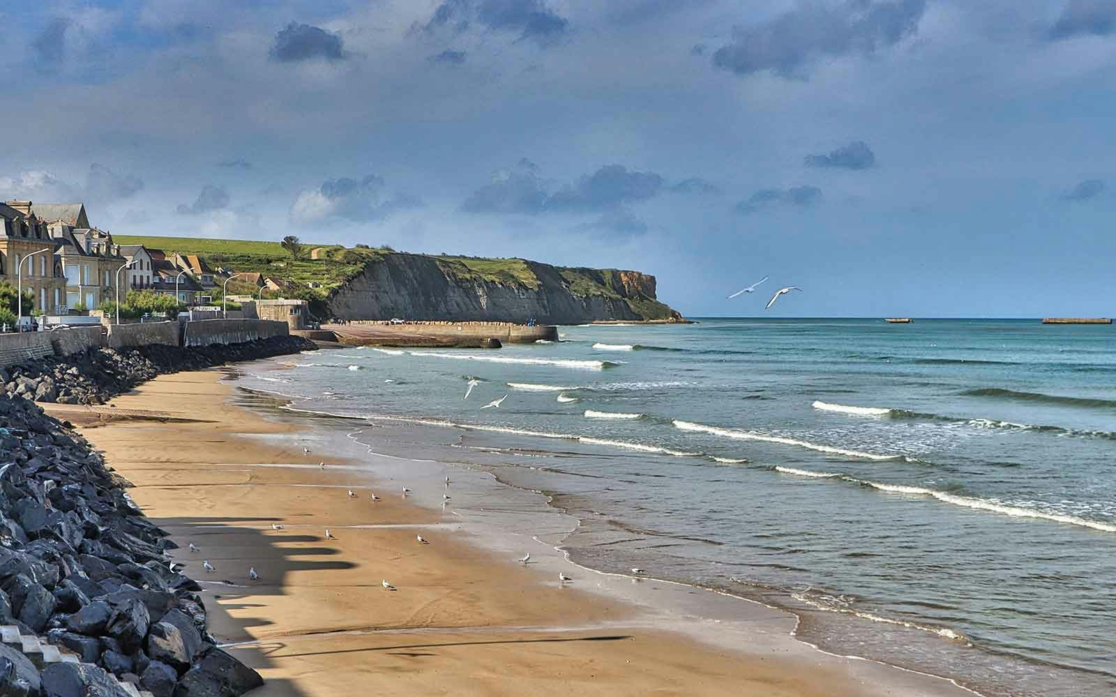 Visitors exploring Gold & Juno Beaches, Normandy, France, with historical bunkers and memorials in view.