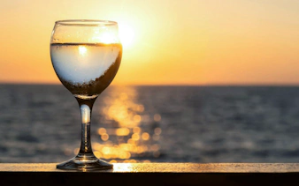 Wine glass on railing with sunset over Blue Lagoon, Ayia Napa cruise.