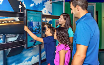 Family interacting with stabilization system exhibit at aviation museum.