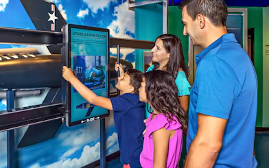 Family interacting with stabilization system exhibit at aviation museum.