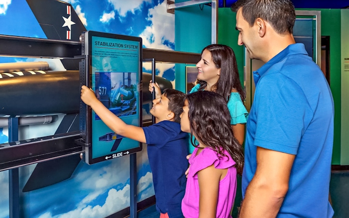 Family interacting with stabilization system exhibit at aviation museum.