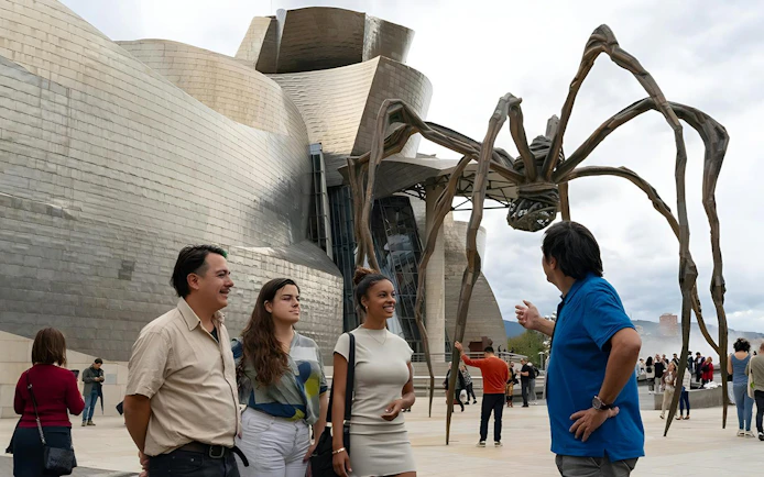 Tourist group with guide in front of Guggenheim Museum Bilbao and "Maman" sculpture by Louise Bourgeois.